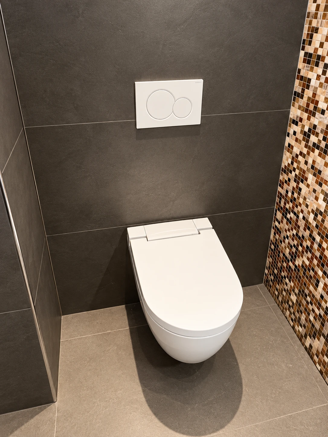 WC suspendu avec plaque de commande, carrelage anthracite et mosaïque